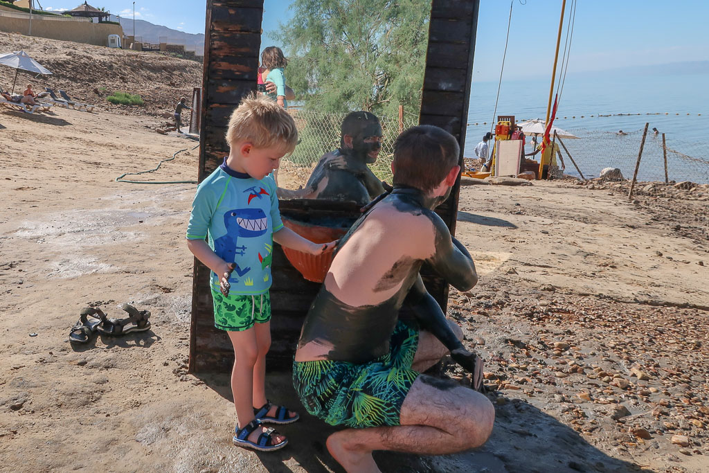 Family applying dead sea mud to body, Jordan